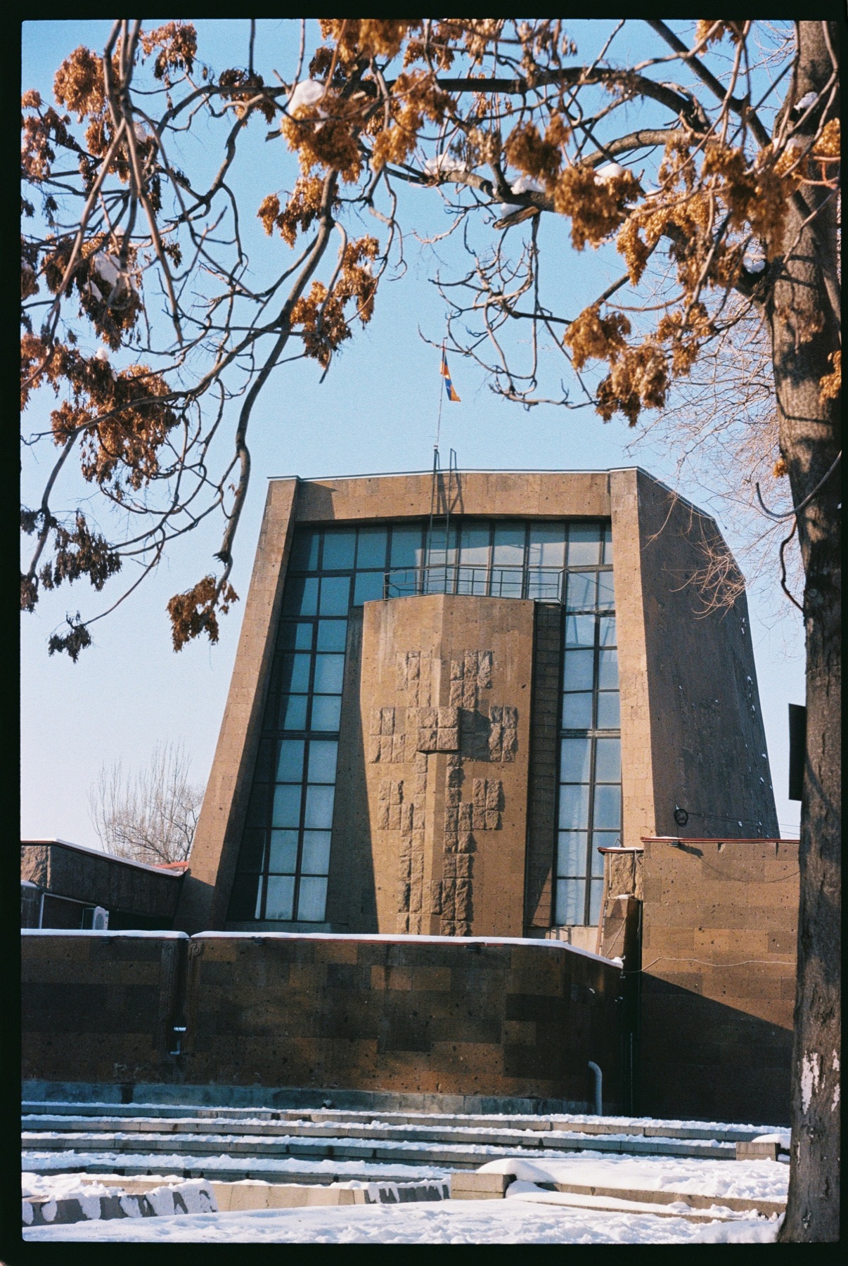 Geometric modernist stone building framed by winter trees in Yerevan