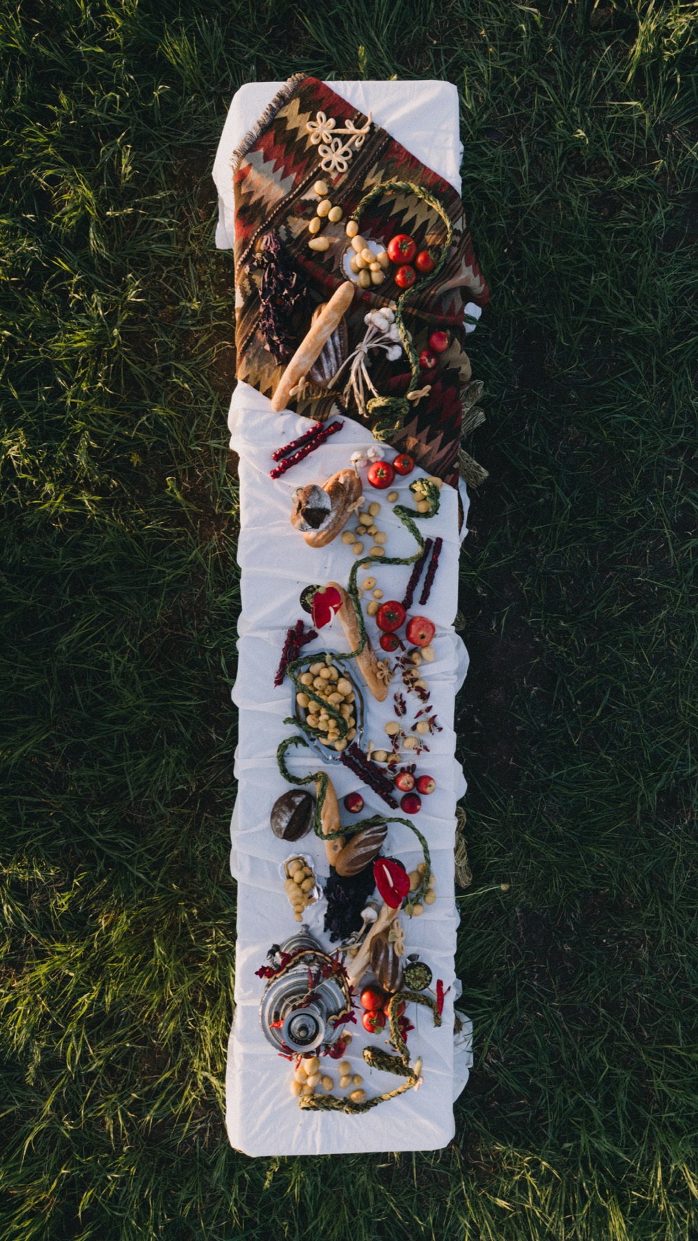Long outdoor table set with bread, vegetables, and Armenian dishes